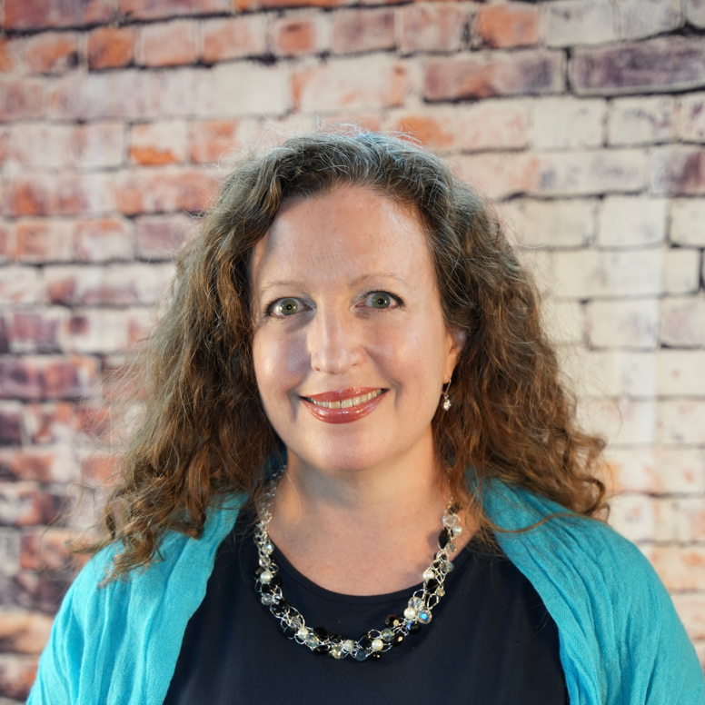 Professional headshot-style portrait of Emily Tell in a modern workspace, friendly and confident.